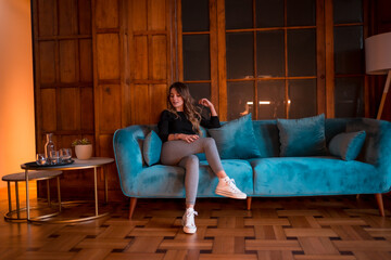 Obraz premium A young Caucasian woman sitting on a blue sofa in a traditional wooden house
