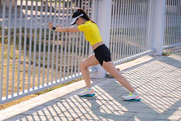 A young beautiful Asian woman in sports outfits doing stretching before workout outdoor in the city stadium  in the morning to get a healthy lifestyle. Healthy young woman doing excercise