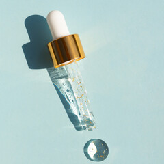 Close-up pipette with a hyaluronic moisturizing 24k gold serum on a blue background. Beauty skin...