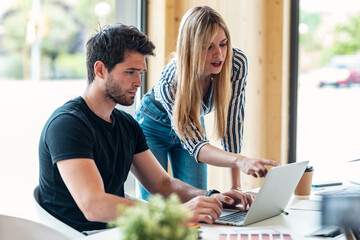 Smart business people working together with laptop while talking in the coworking place.