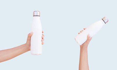 Female hands holding two white reusable steel bottles on blue background.