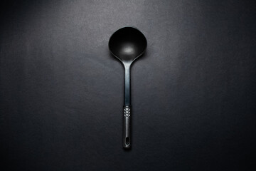 Studio picture of big black plastic dipper with chromed handle.