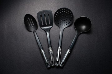 Studio picture of black plastic kitchen utensils with chromed handles.