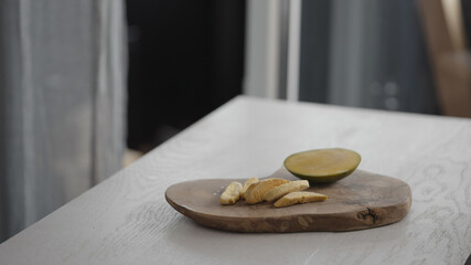 Sublimated mango next to fresh mango on olive board on white oak table