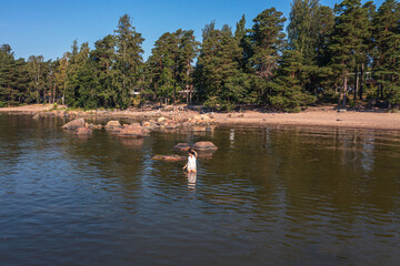 A young woman walks on the water. Lady bathes. Concept of summer vacation, skin and health care, relaxation.