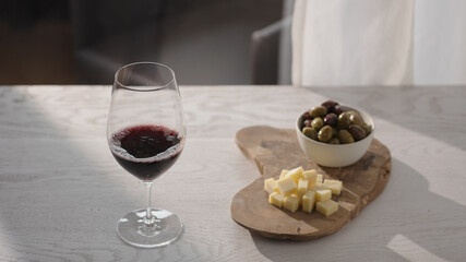 Red wine in wineglass with antipasti on white oak table