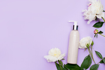 Natural herbal lotion concept. Cosmetic product bottle with blossom flowers peonies on purple background. branding mock-up, copy space.