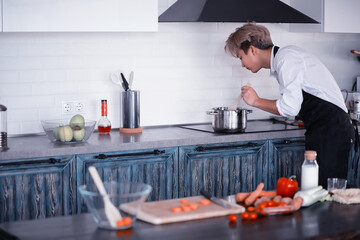 Asian cook in the kitchen prepares food in a cook suit