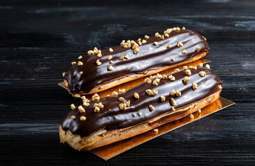 Traditional French dessert. Eclair with chocolate. Dark background