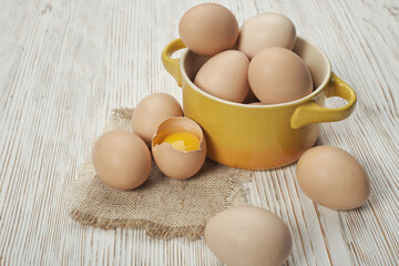 Bowl of raw chicken eggs on the wooden background