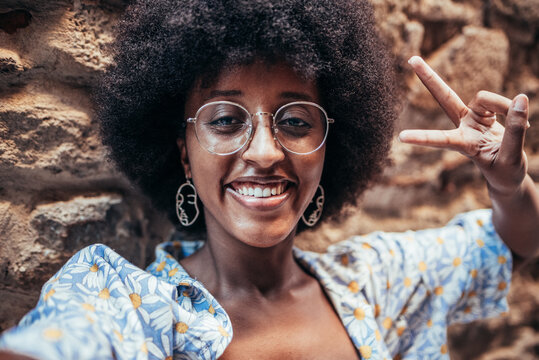 self picture of a cheerfil african woman. She is smiling and is doing victory symbol with her fingers. Concept of happiness and positivity