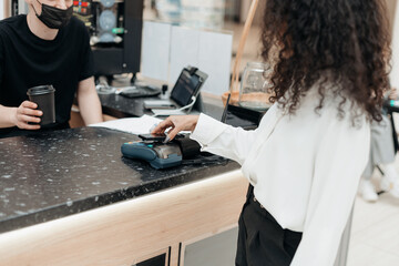 young woman using her smartphone to pay at the supermarket.