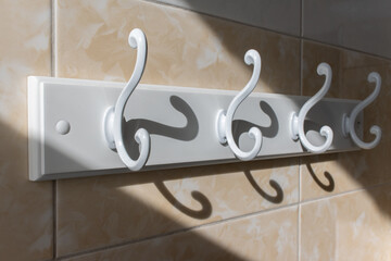 White clothes hanger on the wall tiled and lit by the sun