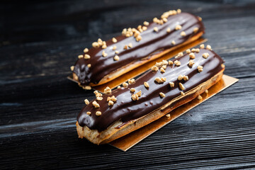 Traditional French dessert. Eclair with chocolate. Dark background