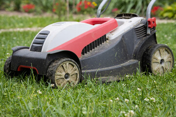 Fototapeta na wymiar An old plastic electric lawn mower stands on a mowed lawn