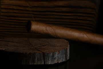 the cigar lies on a wooden stand.