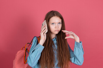 Little kid girl 13 years old isolated on pink background schoolgirl with backpack with mobile phone boring listen voice message, having conversation