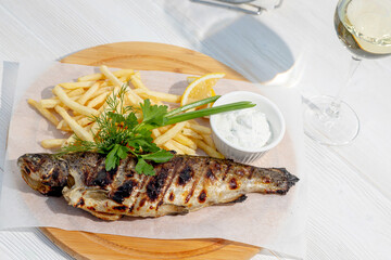grilled fish garnished with herbs and fries
