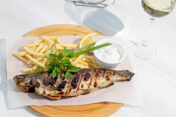 grilled fish garnished with herbs and fries