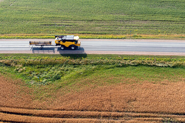 combine harvester on the road between agricultural fields, aerial view