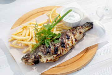 grilled fish garnished with herbs and fries