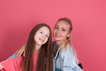 Modern mom and daughter in denim jackets on terracotta background hugging and smiling