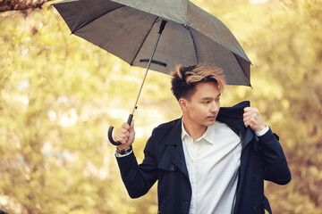 Autumn rainy weather and a young man with an umbrella