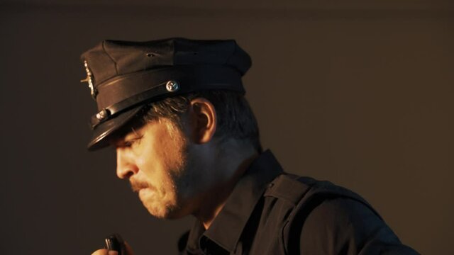 a male police officer speaks on a walkie-talkie while patrolling a close-up portrait