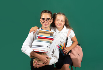 Little school girl with pile of books. Teen student carry a book. Hard to study. Sisters hugging and ready to school.