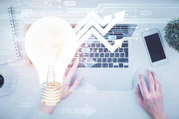 Double exposure of woman hands working on computer and light bulb hologram drawing. Top View. Idea concept.