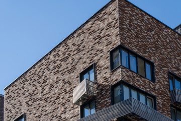 Close-up view of mounting for outdoor air conditioner on facade of new high-rise building made of decorative bricks with windows and elegant metal elements