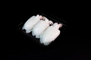 Fototapeta na wymiar fresh cuttlefish arranged in a condo put food on a black background For grilling and bbq 