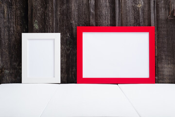 white and red blank picture frames, white table, old wooden wall
