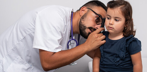 Pediatrician examining the ears of her little patient