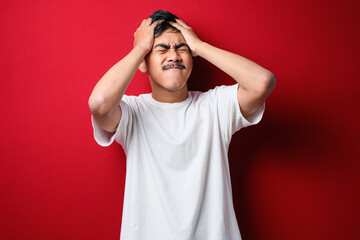 Young handsome asian man wearing white t-shirt with hand on head for pain in head because stress. Suffering migraine.