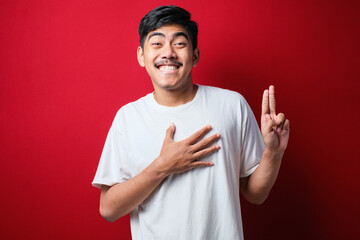Young handsome asian man wearing casual shirt smiling swearing with hand on chest and fingers up,...