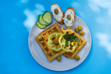 Delicious salted waffles with vegetables, peppers, olives, and cucumber. Breakfast with waffles and...
