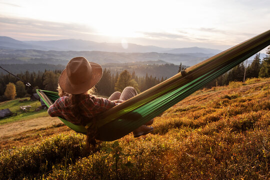 Woman hiker resting after climbing in a hammock at sunset