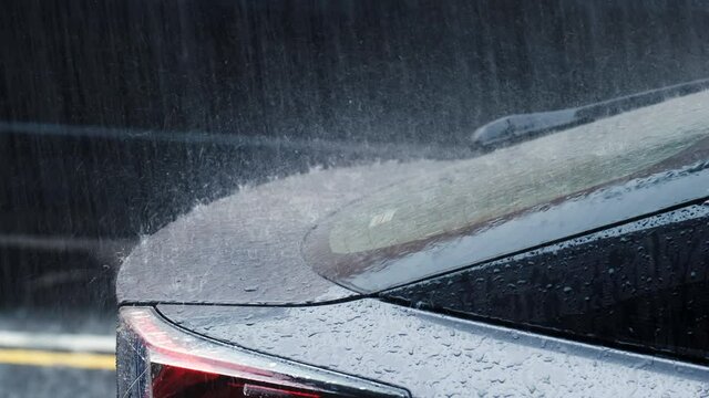 Slow motion of heavy rain on roof of car.
