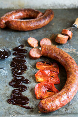 Loukaniko, deftige griechische Schweinswurst, gegrilt, mit tomatenscheiben und BBQ-So&szlig;e