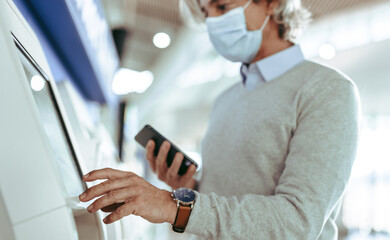 Obraz na płótnie Canvas Man making self check in at airport during pandemic