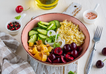 Healthy Salad Bowl with Bulgur, Cherry, Cheese, Cucumber and Walnuts on a light concrete background. Healthy food.