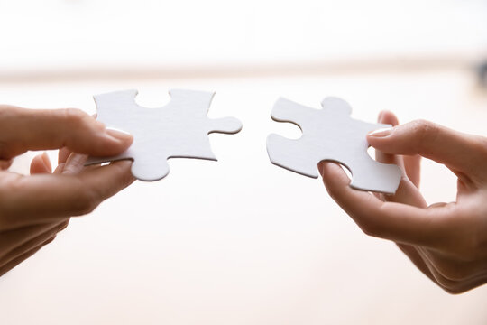 Human connecting two pieces of puzzle. Woman joining jigsaw parts. Business person offering great solution for client needs, finding best problem solving. Perfect match in partnership concept
