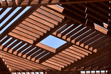 Obraz na płótnie Canvas closeup of outdoor wooden cell ceiling pattern with blue sky between grid,design of exterior architecture ceiling at luxor egypt.simple design of ceiling.brown wooden ceiling