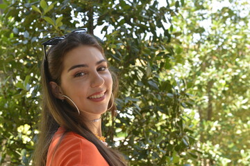 Young girl smiling in the garden. Young women portrait. Garden background with trees. Summer season