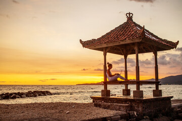 Woman by the ocean working on a laptop