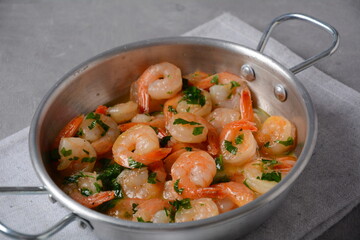 Shrimp scampi with garlic and butter sauce sprinkled with parsley, on a skillet. Keto diet dish