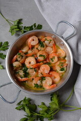 Shrimp scampi with garlic and butter sauce sprinkled with parsley, on a skillet. Keto diet dish