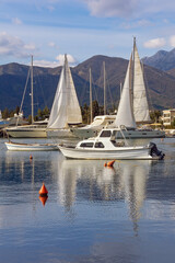 Obraz premium Beautiful winter Mediterranean landscape. Sailboats and fishing boats on water. Montenegro, Adriatic Sea. View of Kotor Bay near Tivat city