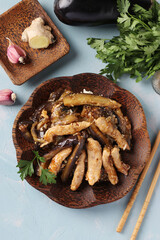 Chicken with eggplant in a spicy sauce. Delicious Asian homemade snack on light blue table. Top view. Close-up